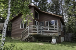 Image of This three bedroom cabin is tucked into the majestic northwoods. Two of the bedrooms have queen sized beds and the third bedroom has two twin-sized beds. The cottage is completely furnished, offers a natural stone fireplace, and has a full kitchen.